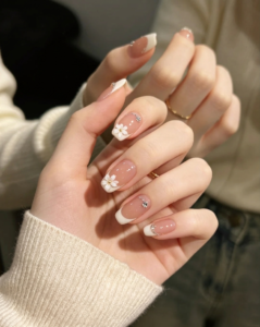 Glossy pink French manicure nails with small flowers at the tips.