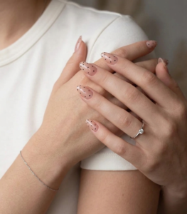 Elegant and youthful nude pink almond-shaped nails with polka dots.