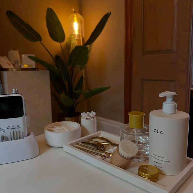 Elegant desk setup representing the quiet luxury nail aesthetic, featuring neutral-toned skincare and professional nail care tools.