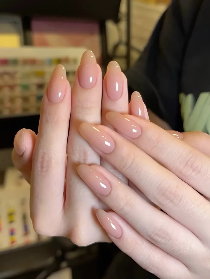 Barely-there nude-pink nail polish creating a seamless and sophisticated look.