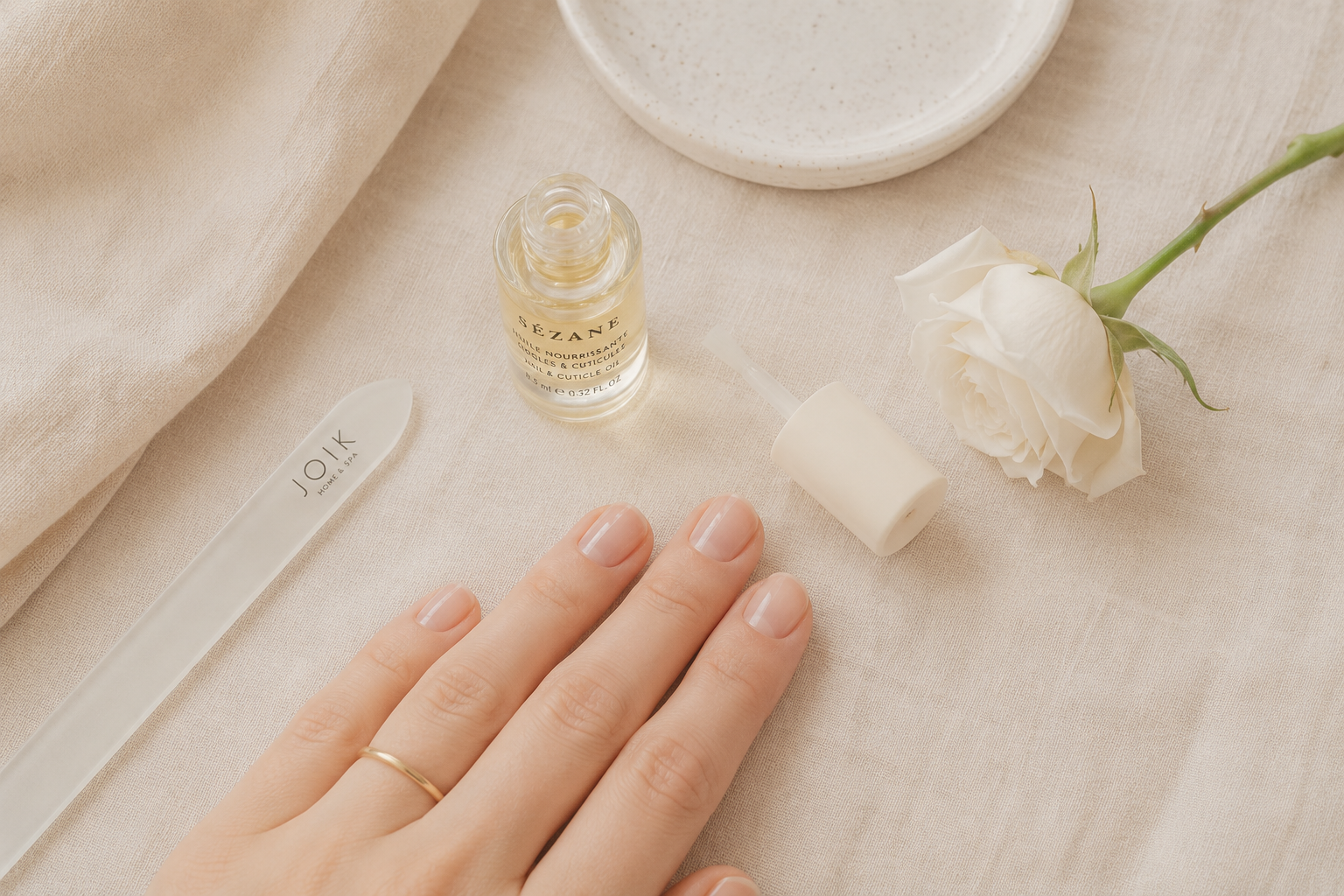 Short clean nails styled in a soft neutral tone, resting on a linen surface for a quiet luxury aesthetic.