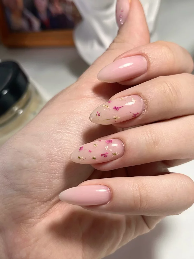 Natural pressed wildflower elements embedded in a sheer soft pink nail manicure.