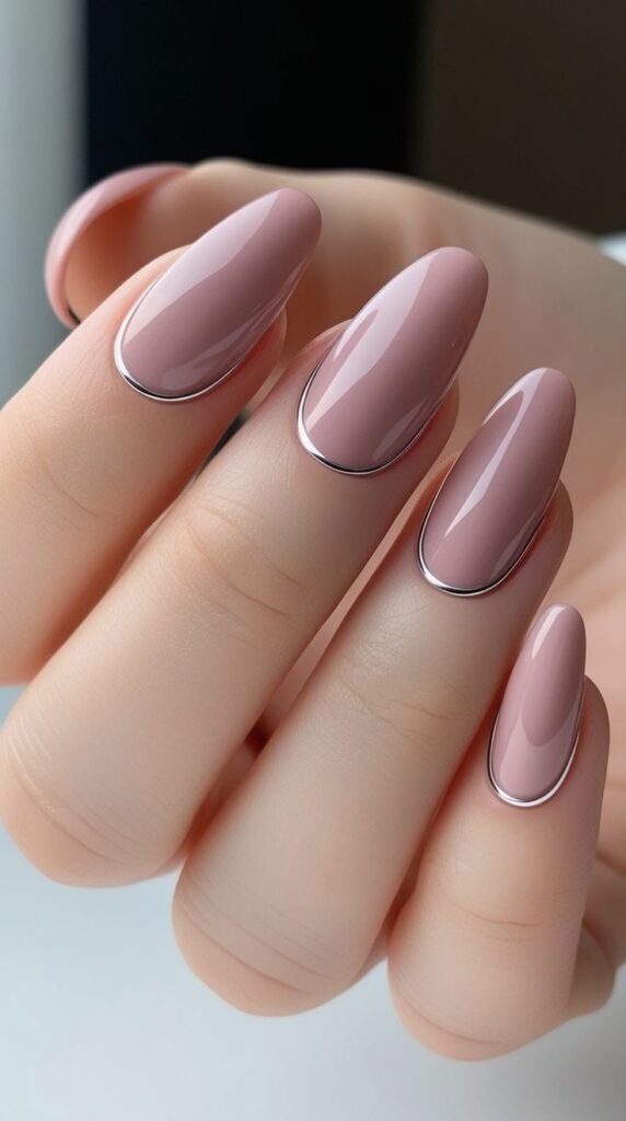 Soft mauve almond nails with delicate metallic cuticle accents, creating an elegant and modern minimalist manicure.