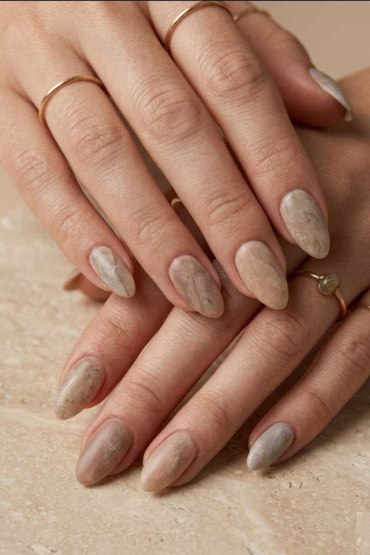 Tone-on-tone beige marble nails with soft neutral patterns and an understated luxury feel.