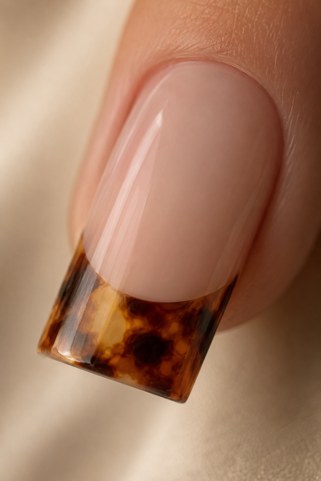 Extreme close-up of a tortoiseshell French tip nail with amber, caramel, and chocolate marbling detail for a refined fall manicure look.