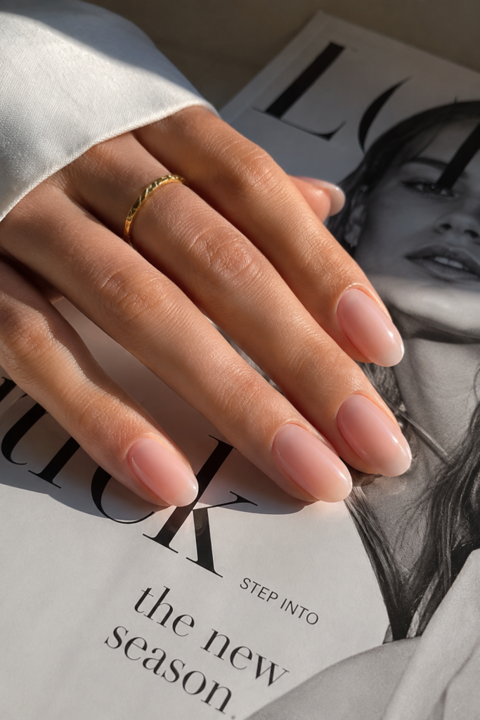 Glossy nude Clean Girl Nails styled with a fashion magazine and soft neutral tones, creating an elegant quiet luxury manicure aesthetic.