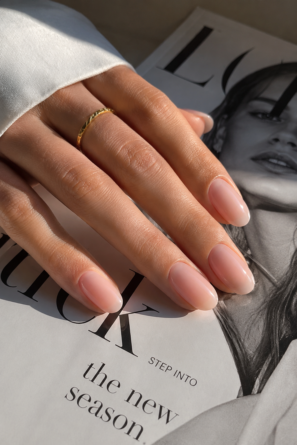 Glossy nude Clean Girl Nails styled with a fashion magazine and soft neutral tones, creating an elegant quiet luxury manicure aesthetic.