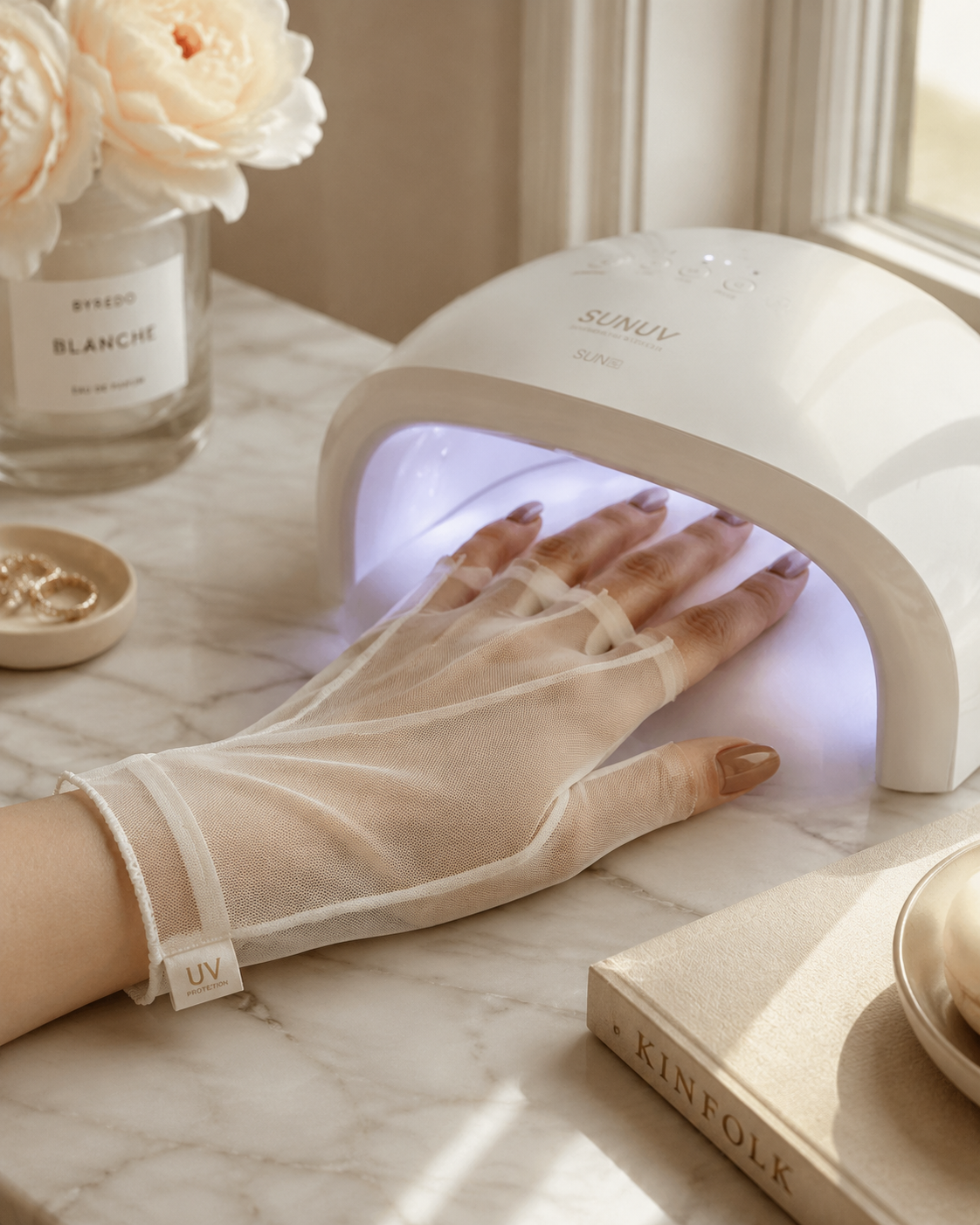 Hand wearing fingerless UV gloves resting under an at-home UV nail lamp during a gel manicure.