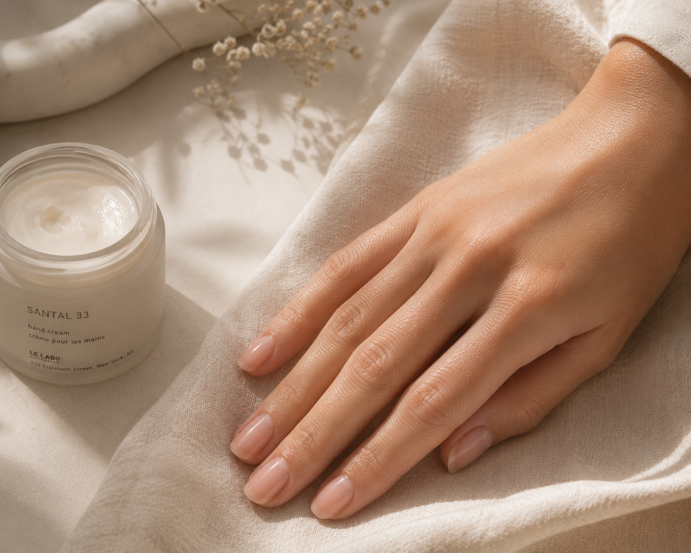 Healthy, softly polished nails resting beside a nourishing hand cream