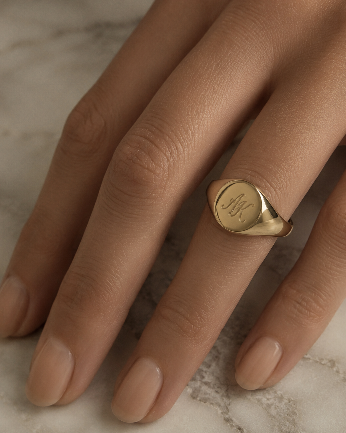Single gold signet ring styled minimally on a manicured hand