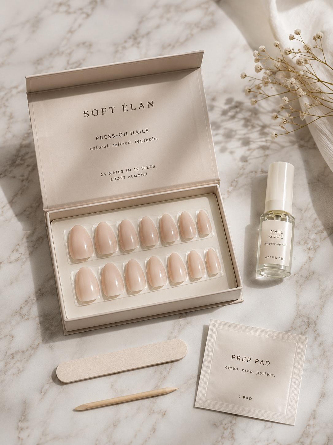 Natural looking press-on nails kit with almond-shaped tips laid out on marble.